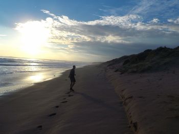 Man walking on beach against sky