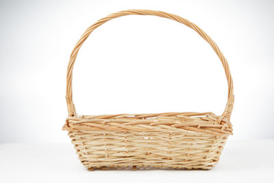 Close-up of wicker basket on table against white background