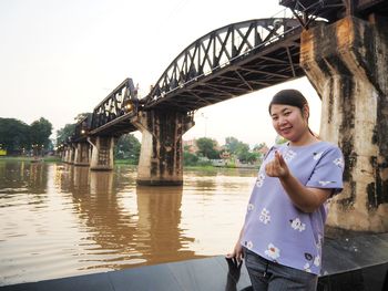 Young woman standing on bridge against sky