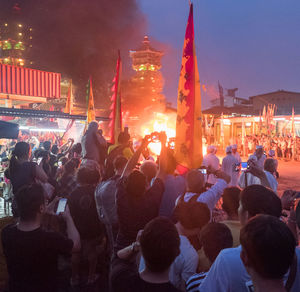 Crowd in front of illuminated temple against sky at night