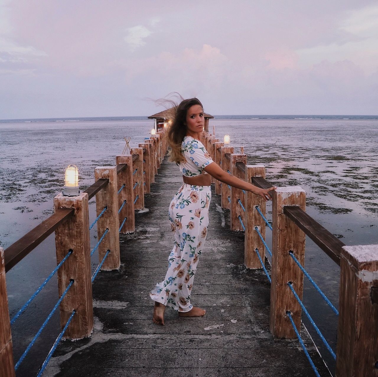 WOMAN STANDING AT BEACH AGAINST SKY