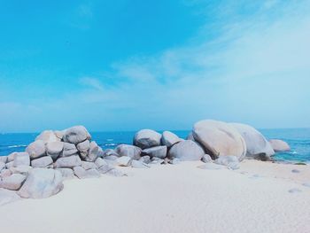 Rocks on beach against blue sky