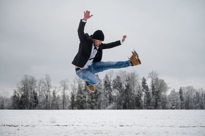 Low angle view of boy standing on snow covered field against sky