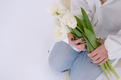 Midsection of woman with bouquet against white background