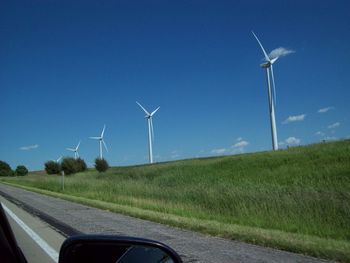 Wind turbines on road against clear sky