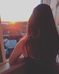 Rear view of woman standing by window