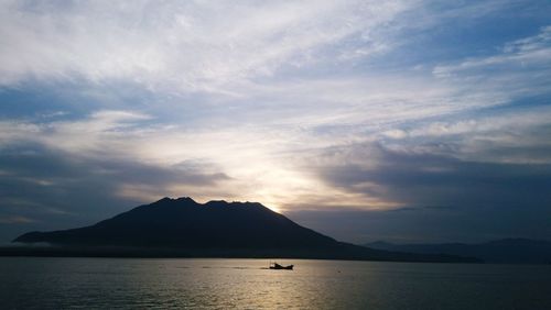 Scenic view of mountains and river against cloudy sky during sunset