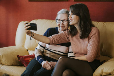 Granddaughter and grandmother taking a selfie on the sofa