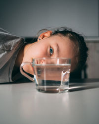 Portrait of boy drinking water from glass on table