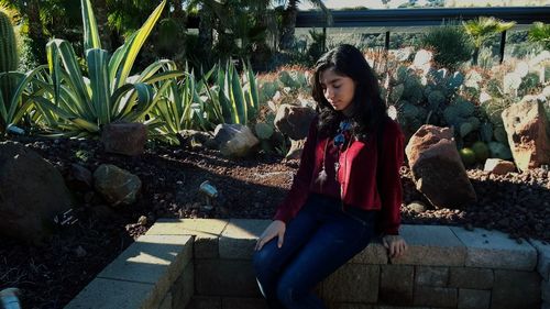 Young woman smiling while sitting by tree