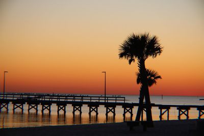 Silhouette palm trees on beach against clear sky during sunset