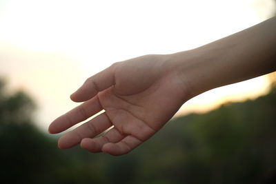 Close-up of hand holding hands against sky