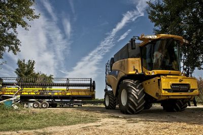 Thresher in farm against sky