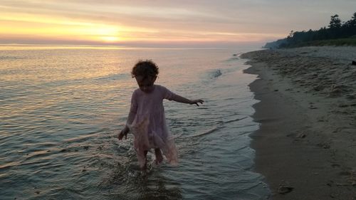 Rear view of woman on beach during sunset