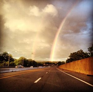 Rainbow over road against sky