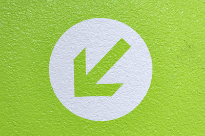 Close-up of arrow sign on green background