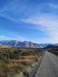 Road leading towards mountains against sky