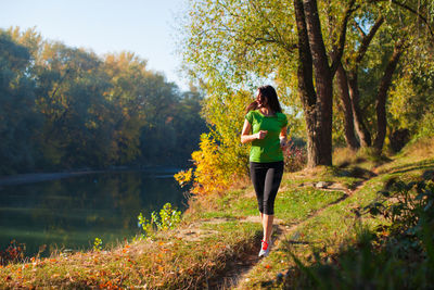 Full length of woman standing amidst trees in forest