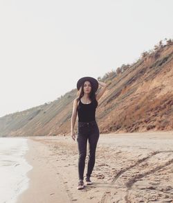 Portrait of young woman standing on mountain against clear sky