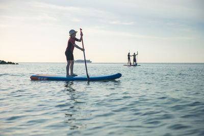 Men standing on boat in sea against sky