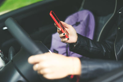 Trendy blonde girl sitting in the car use smartphone teen in front of the steering wheel young woman