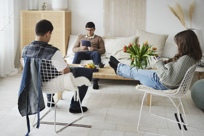 Teenagers sitting in living room and using phones and tablet