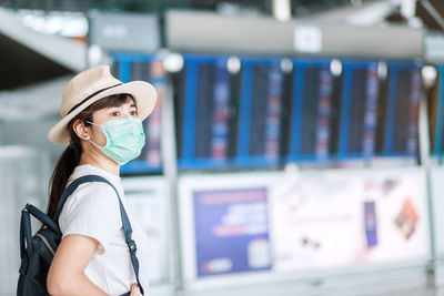 Close-up of woman wearing mask looking away standing at airport