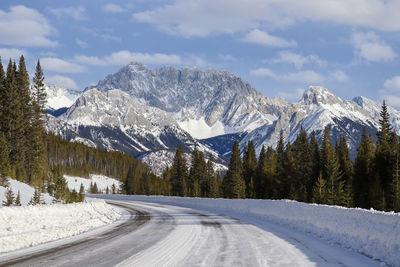 Road amidst snowcapped mountains against sky during winter