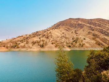 Scenic view of lake and mountains against clear blue sky