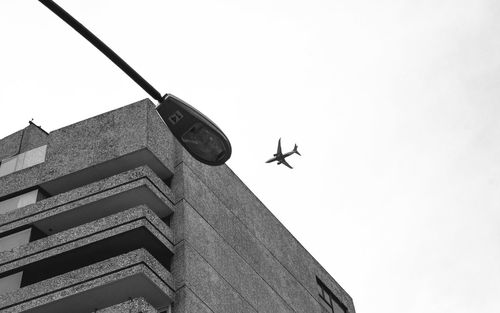 Low angle view of airplane flying above building