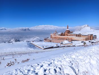 Snow covered buildings against blue sky