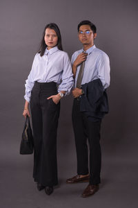 Portrait of friends standing against gray background