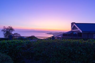 Houses by buildings against sky during sunset