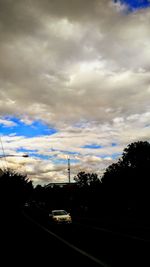 Cars on road against cloudy sky