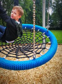 Boy playing on swing in park