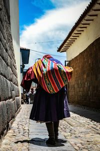 Rear view of woman walking on multi colored umbrella