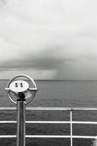 Close-up of coin-operated binoculars by sea against sky