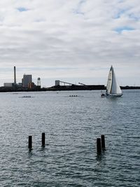 Sailboats in sea against cloudy sky