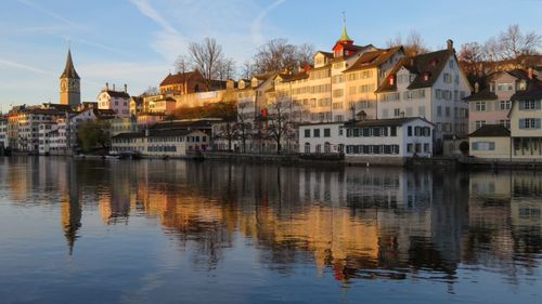 Buildings by river against sky in city