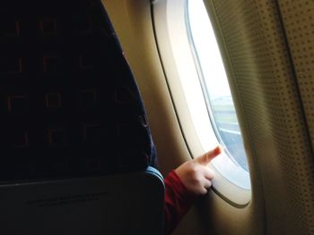 Cropped image of child touching airplane window