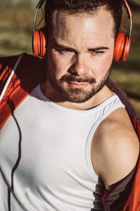 Close-up of young man wearing headphones looking away outdoors