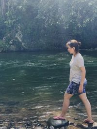 Full length of young woman standing by sea