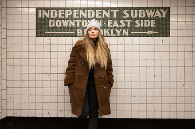 Portrait of young woman standing against text onn wall