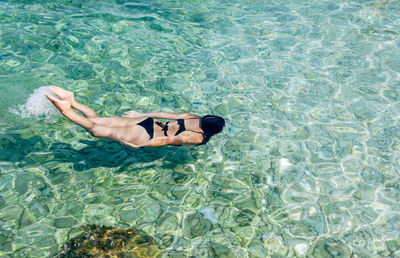 High angle view of woman swimming and diving in turquoise colored sea water.