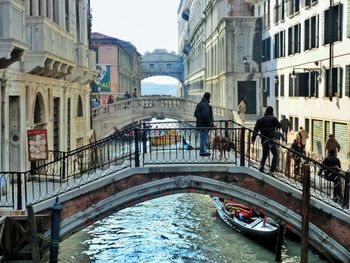 People on bridge over canal in city