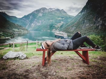 View of man sitting on bench against mountain range