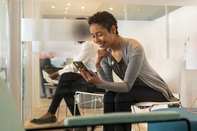 Young woman using phone while sitting on seat