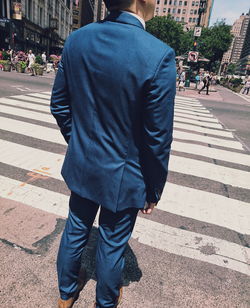 Rear view of businessman standing on zebra crossing in city during sunny day