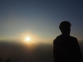 Rear view of silhouette man standing against sky during sunset