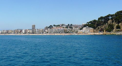 Sea by city against clear blue sky